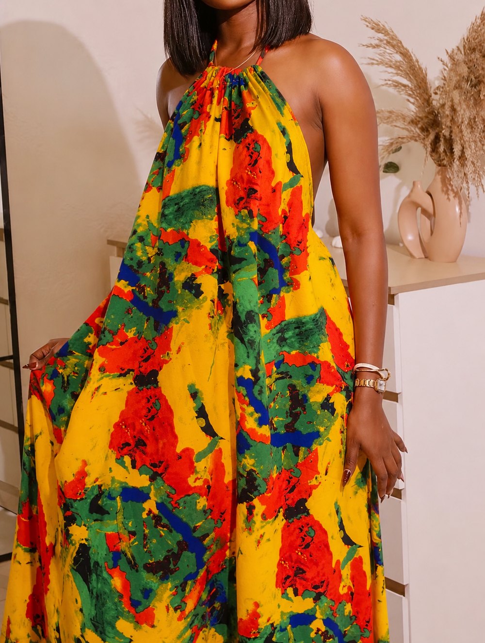 Woman in a yellow, red and green printed halter-neck maxi dress